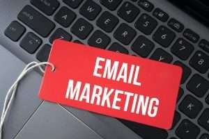 Top view of red paper and the text email marketing on a laptop background.